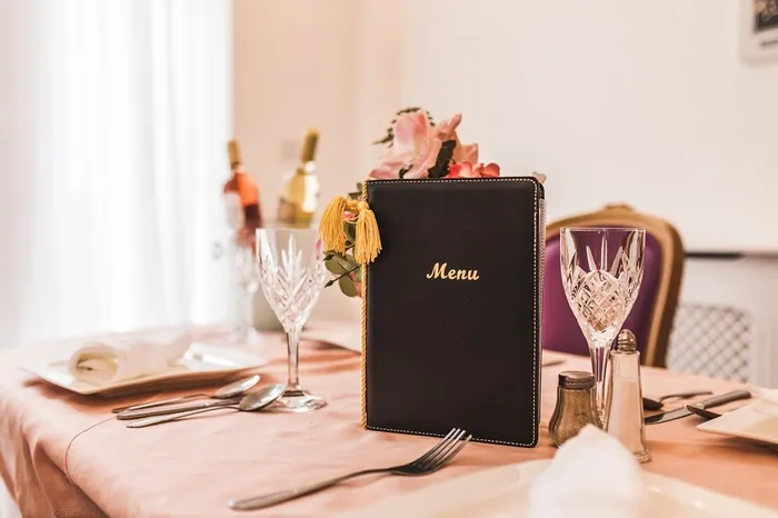 A place setting with a menu, wine glasses and folded napkins