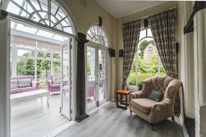 A sunlit room with arched windows and armchairs overlooking the garden