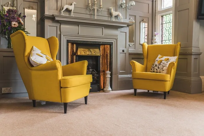 Two yellow armchairs in front of the fireplace in a residents' lounge